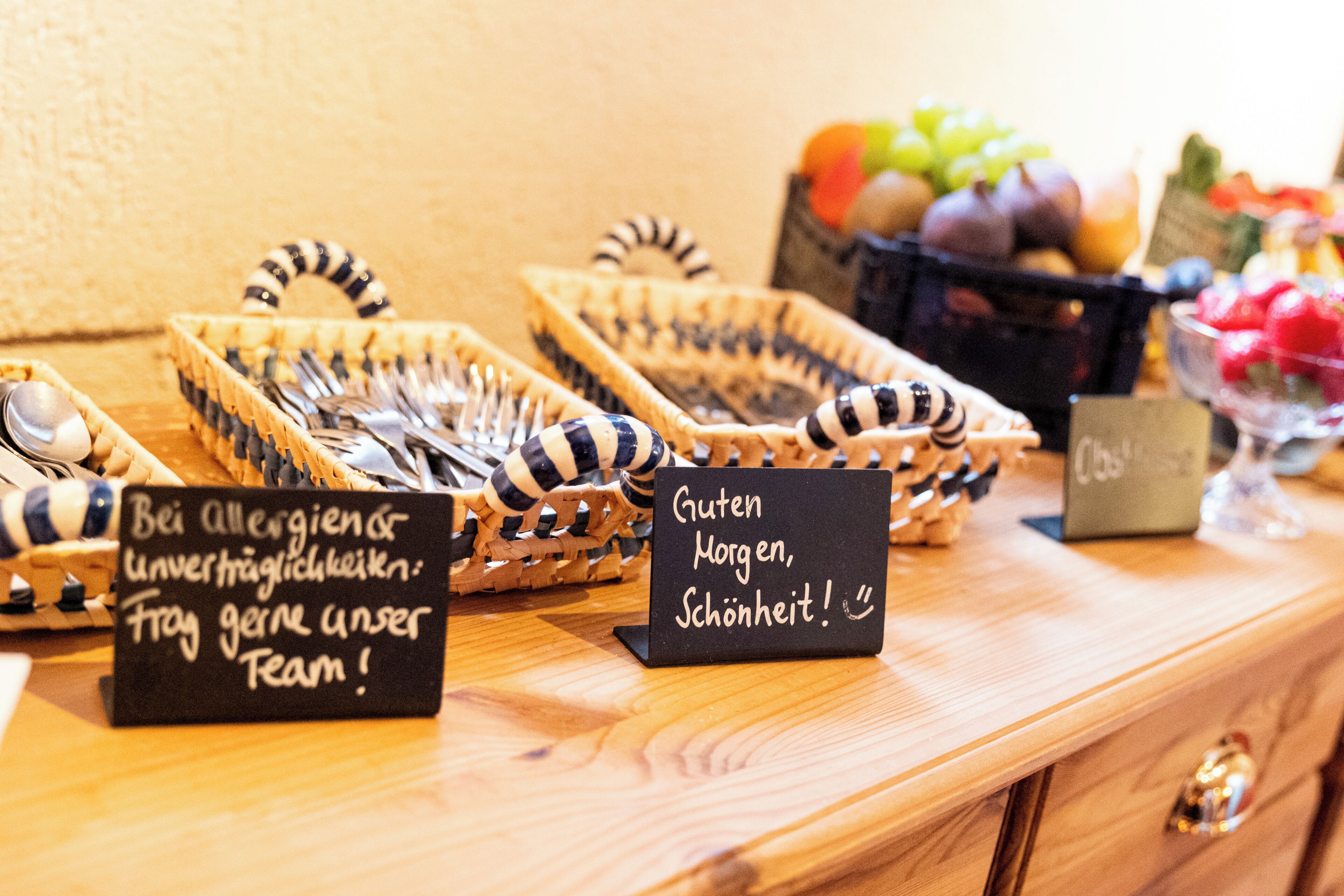 A wooden table with baskets containing utensils and a sign with a message.