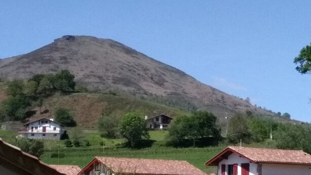 Una montaña con una pequeña casa en su base.