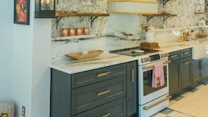 Una cocina con muebles oscuros, una estufa blanca y piso de pisos a cuadros.