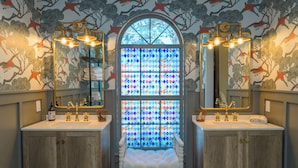 Un baño con dos lavamanos, un espejo grande y una ventana de vitral.