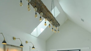 Un salón espacioso con techo alto, un ventanal grande y una viga de madera rústica.