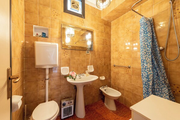 A bathroom with a toilet, bidet, sink, and shower.