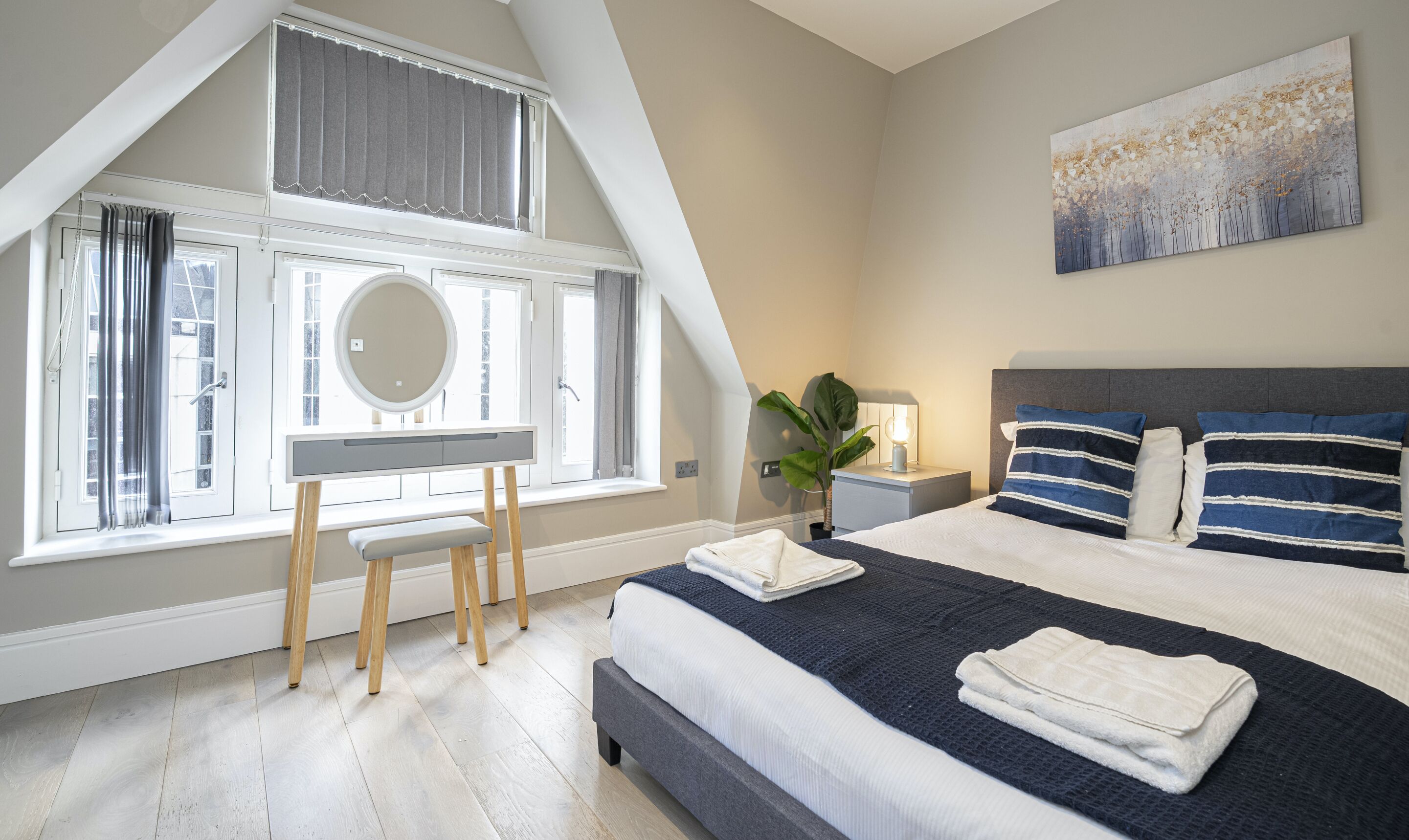Une chambre à coucher avec un lit, une table de chevet, une lampe et une grande fenêtre avec des rideaux.