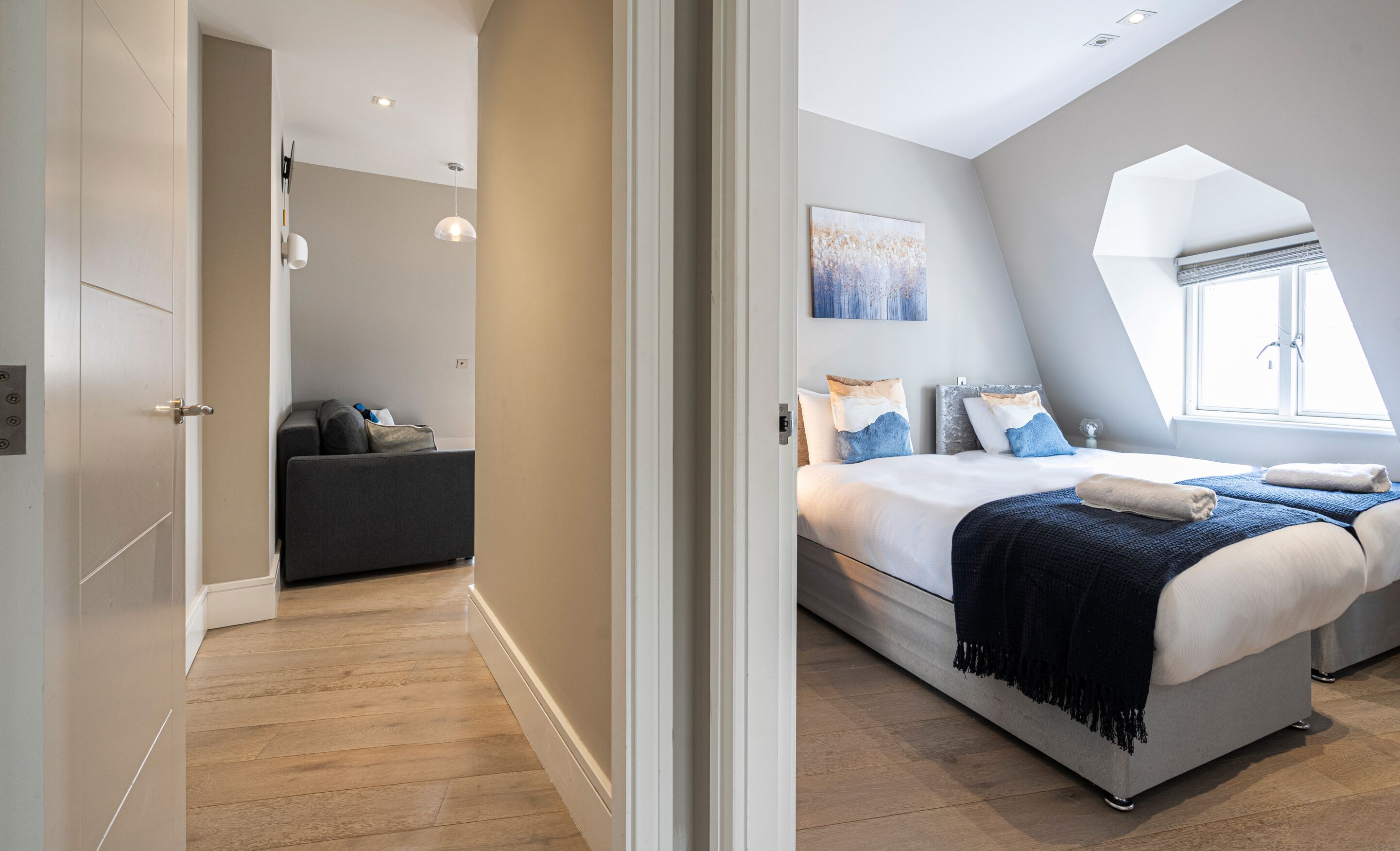A modern bedroom with a large bed, a seating area, and a skylight.