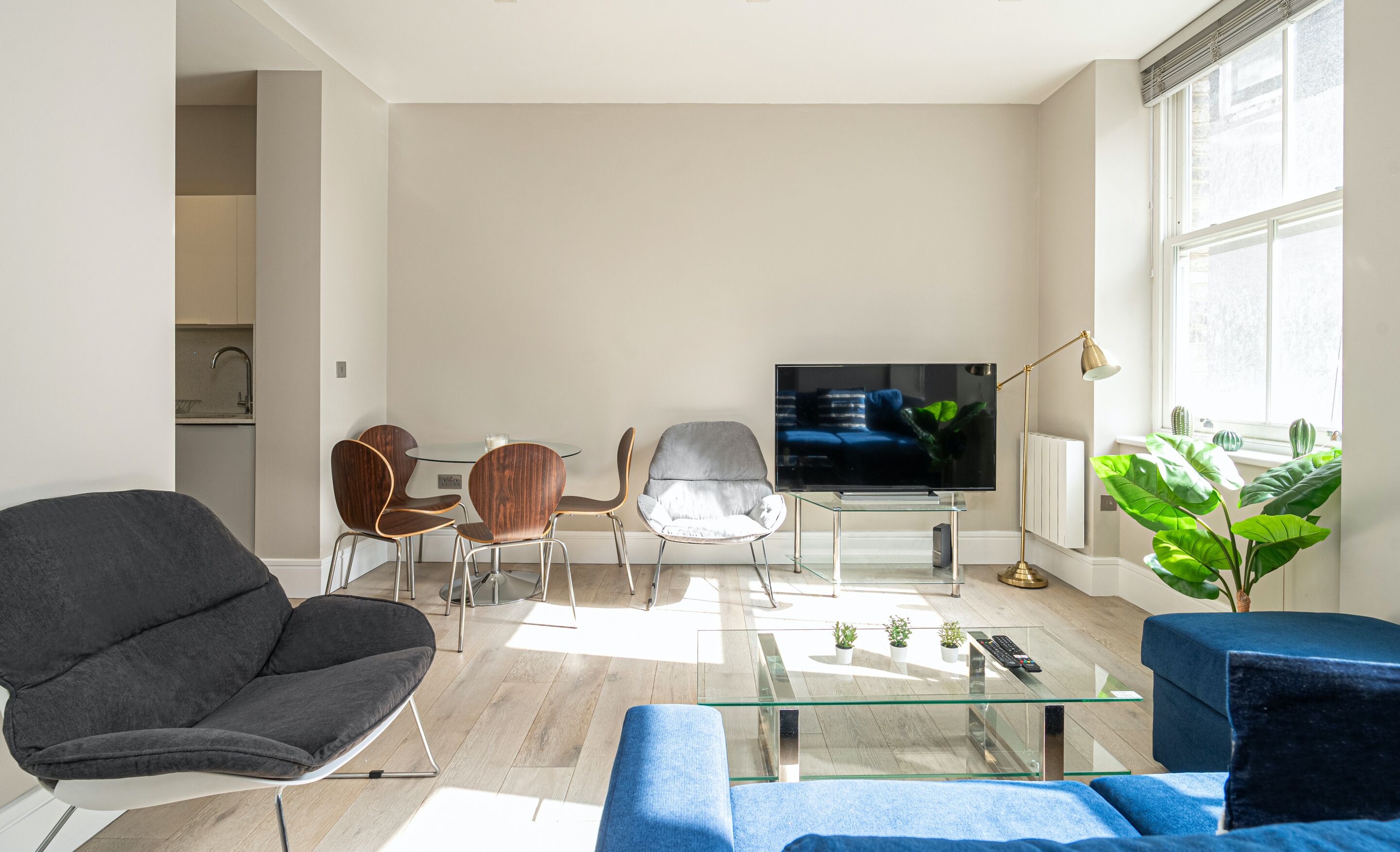 A modern living room with a flat-screen TV, a glass coffee table, and a sofa.