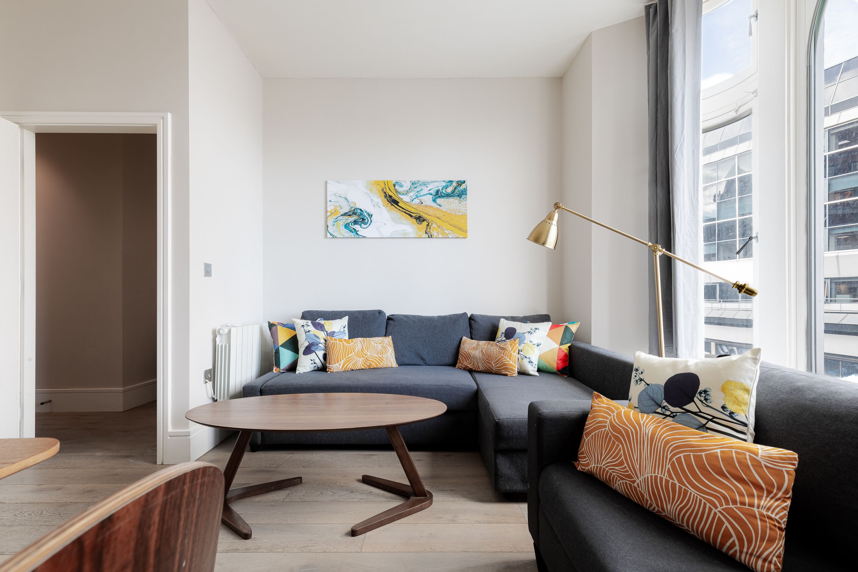 A modern living room with a sectional sofa, a round coffee table, and a floor lamp.