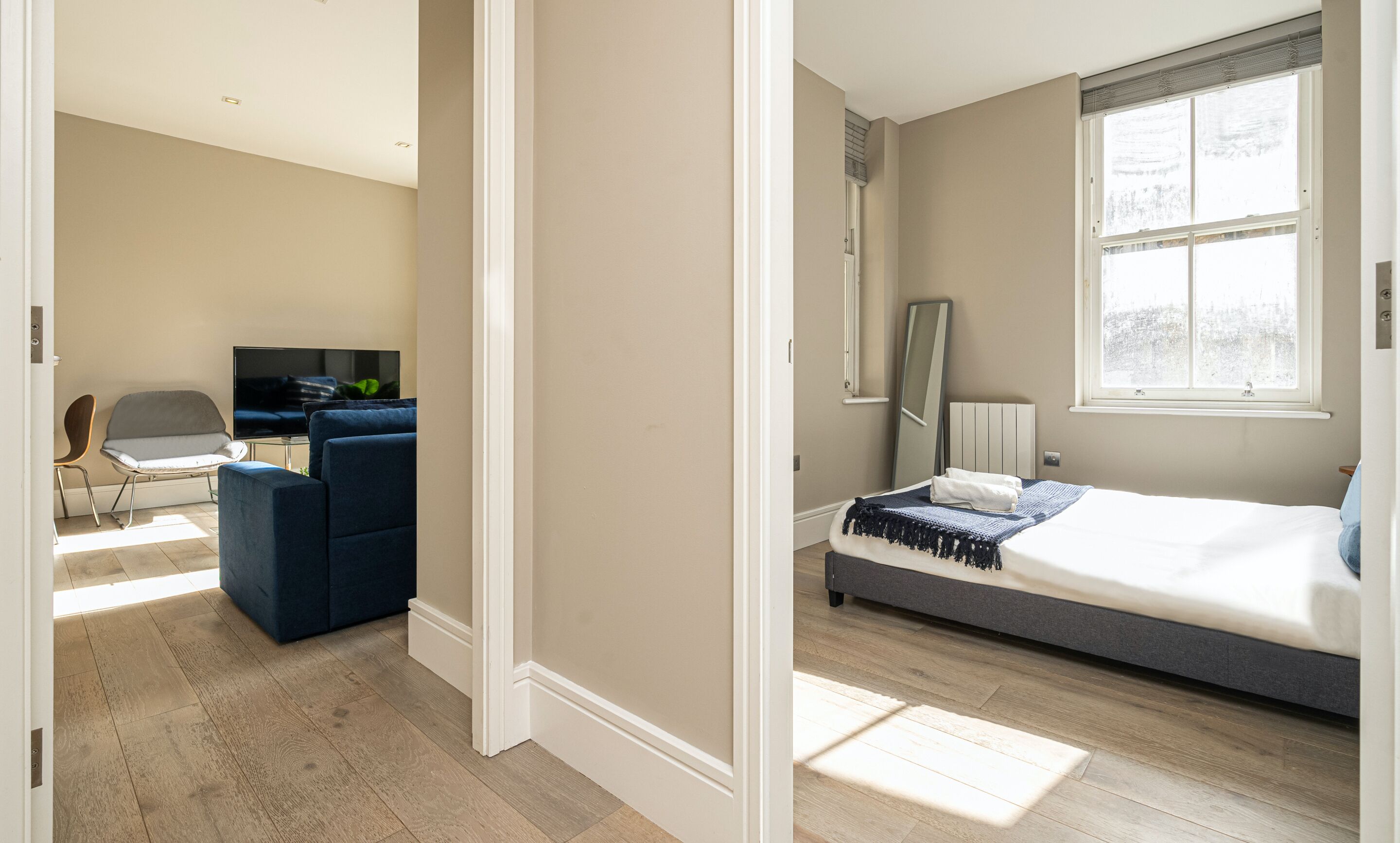 Una habitación con cama, televisión, sillón y escritorio.