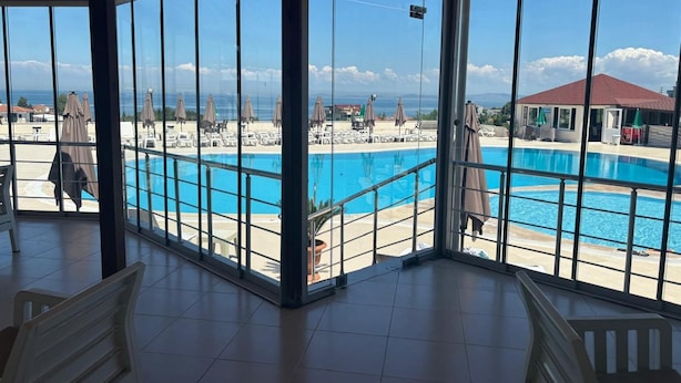 A poolside area with a view of the ocean, a covered seating area, and a pool. - Amadeus Motel (Cinarcik)