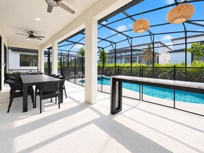 Eine moderne Außenpatio mit Pool, Essbereich mit Tisch und Stühlen sowie Deckenventilator.