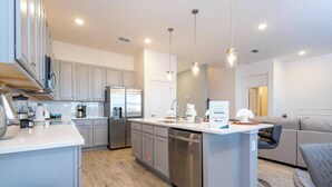A modern kitchen with stainless steel appliances, a central island, and pendant lighting.