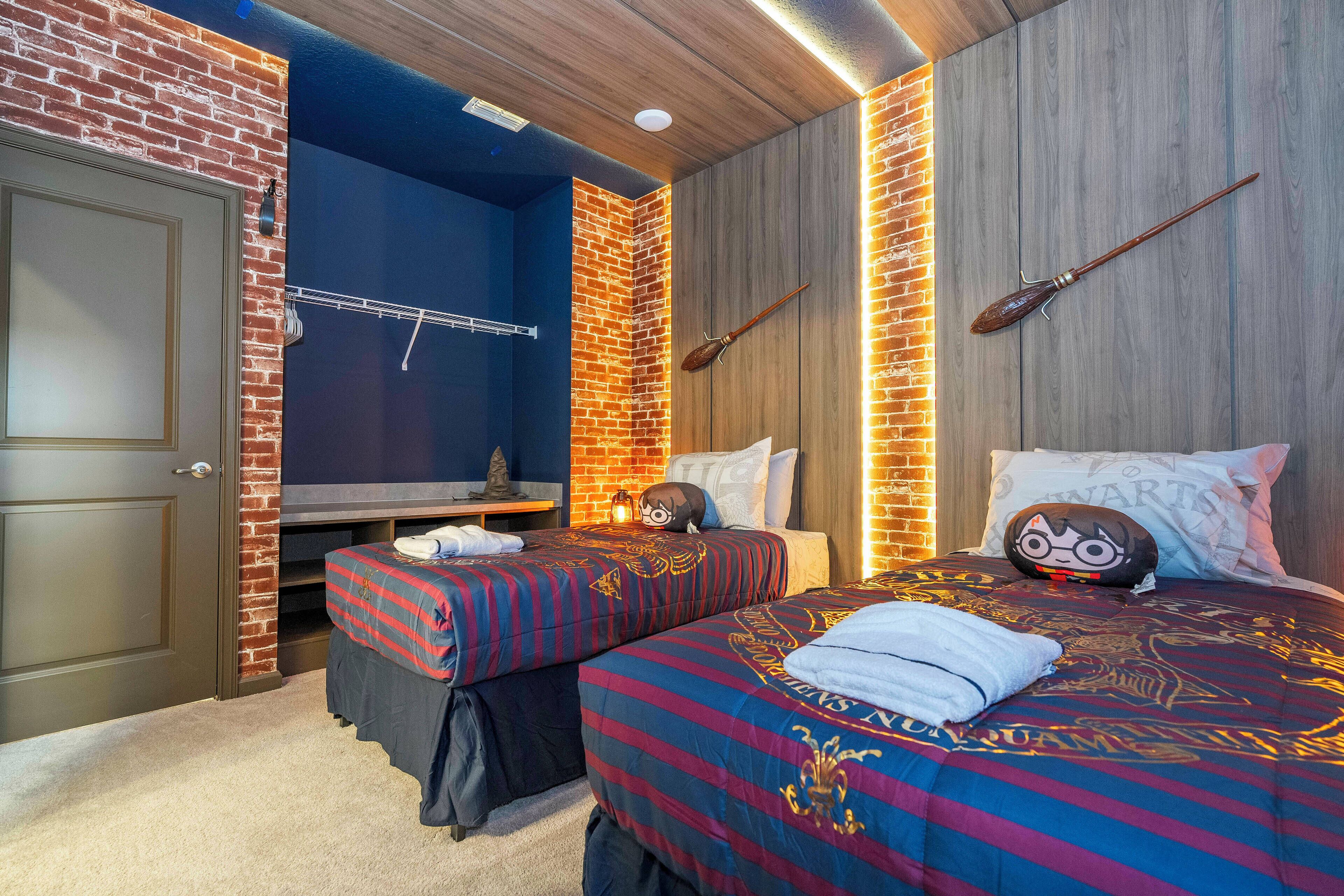 A hotel room with a brick wall, a wooden ceiling, and two beds with themed bedding.