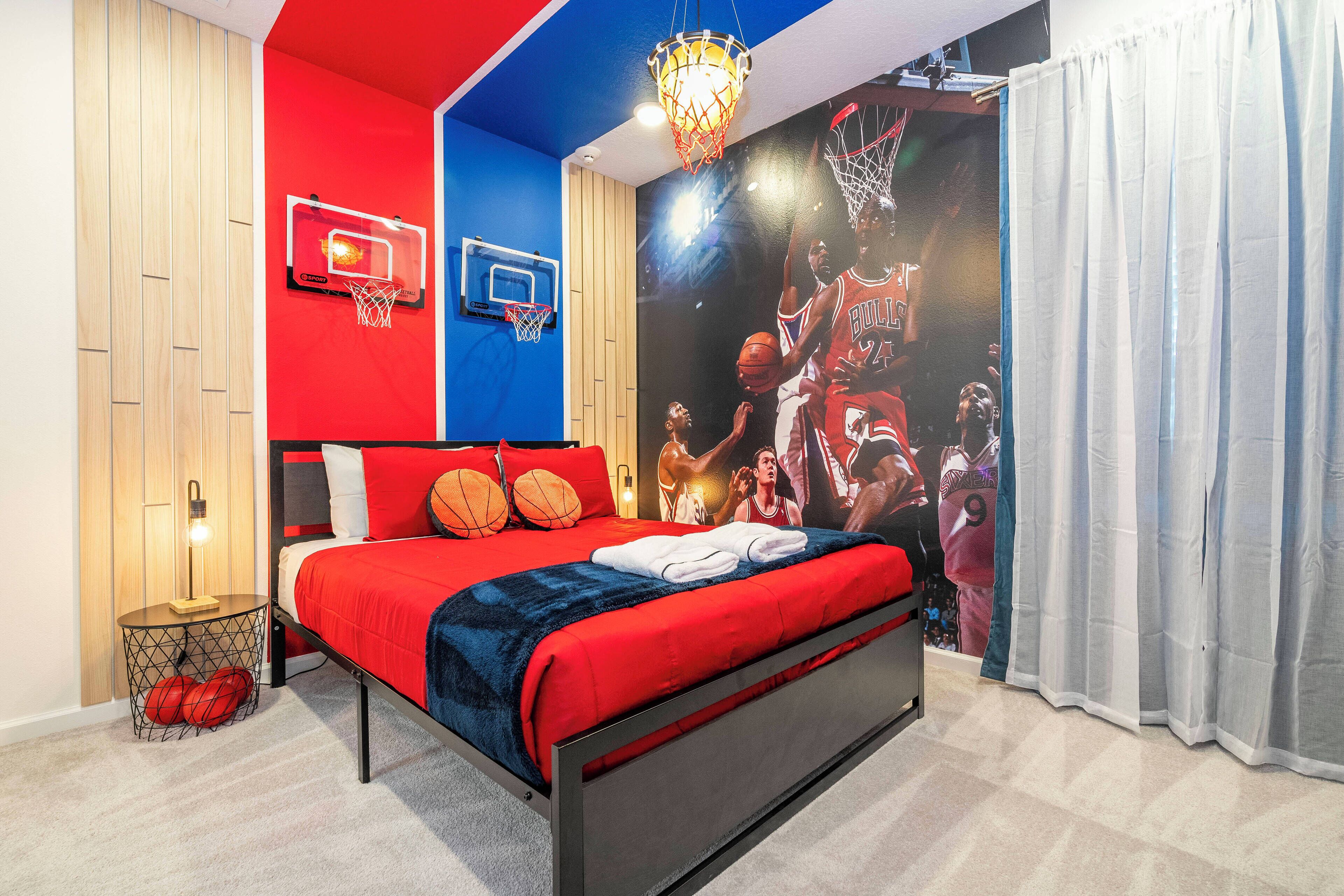 Un dormitorio con cama, dos aros de baloncesto, un mural de jugador de baloncesto y una cortina.