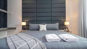 A modern hotel room with a large bed, two bedside lamps, a headboard, and a bedside table. - The Best Home and Location Near Disney (6139PG) (Orlando)