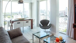 A modern living room with a sofa, a glass coffee table, a dining area with a table and chairs, and large windows offering a city view. - Crystal Clear Bright 1 Bedroom in Palermo Soho (Buenos Aires)