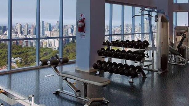 A gym with large windows, weightlifting equipment, and a bench. - Crystal Clear Bright 1 Bedroom in Palermo Soho (Buenos Aires)