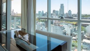 A modern hotel room with a large window offering a city view, a glass table, and a white sofa. - Crystal Clear Bright 1 Bedroom in Palermo Soho (Buenos Aires)