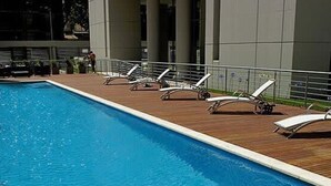 A rectangular swimming pool with a wooden deck and white lounge chairs. - Crystal Clear Bright 1 Bedroom in Palermo Soho (Buenos Aires)