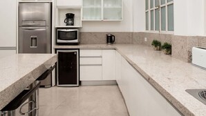 A modern kitchen with white cabinets, stainless steel appliances, a granite countertop, and a window with blinds. - Purple Rain Elegant 2 Bedroom in Recoleta (Buenos Aires)