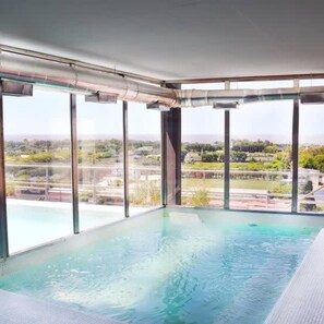 A modern indoor swimming pool with large windows offering a view of a landscaped area. - Green Bliss Spacious Studio in Nu ez (Buenos Aires)