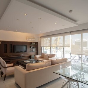 Relax in this stylish living room with a large flat-screen TV, comfortable sofa, and dining area.