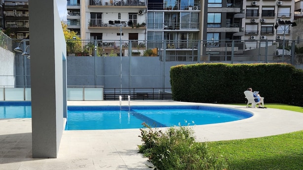 Un edificio residencial con varios balcones, piscina y un jardín bien cuidado.