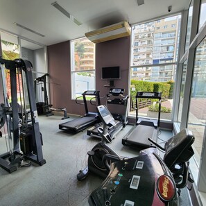 Une salle de sport équipée de tapis de course, d’un vélo d’appartement et d’appareils de musculation.