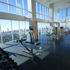 A gym with cardio machines and dumbbells, large windows, and a city view. - Belle View Modern Bright Studio in Palermo Soho (Buenos Aires)