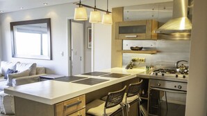 Une cuisine moderne dotée d’un îlot central, de tabourets de bar, d’une cuisinière et d’une grande fenêtre.