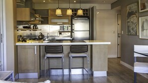 Une cuisine moderne dotée d’un îlot central, de tabourets de bar et de luminaires suspendus.