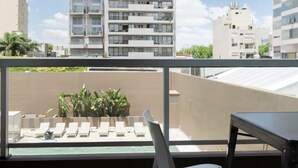 Ein Balkon mit Blick auf moderne Wohngebäude, einem Stuhl und einem Tisch.