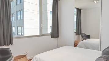 Un dormitorio moderno con una ventana grande, una cama, una silla y un espejo.