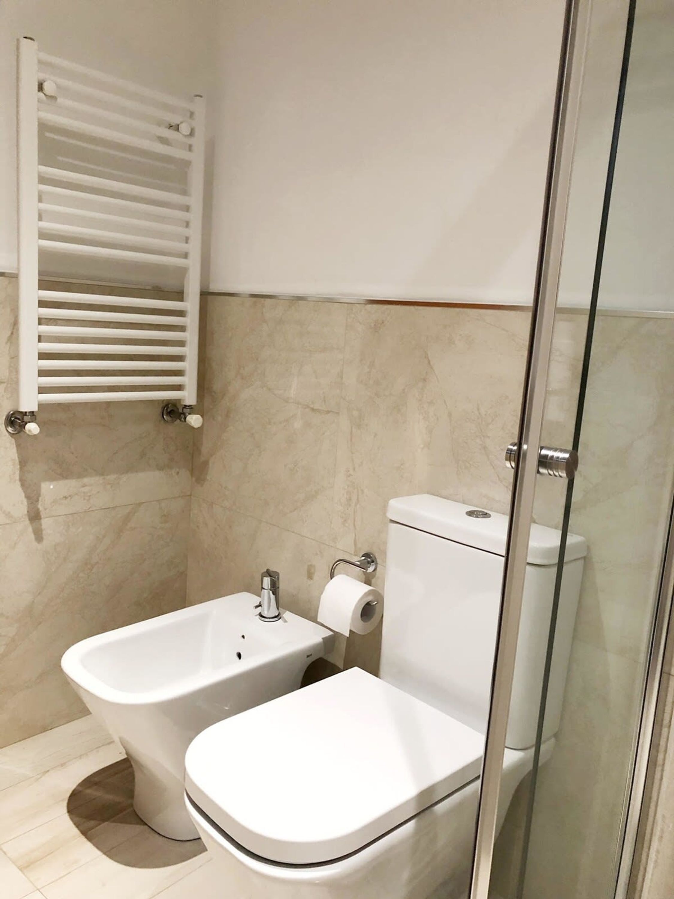 Un baño moderno con cabina de ducha de vidrio, inodoro y bidé.
