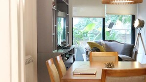 Ein Essbereich mit Holztisch und Stühlen, einem Bücherregal und Blick ins Grüne.