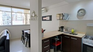 A modern kitchen with a dining area, a trash bin, and a clock on the wall. - Alto Guemes I Spacious 1BR in Palermo (Buenos Aires)