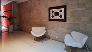 A modern interior with a stone wall, two white chairs, and a framed artwork. - Alto Guemes I Spacious 1BR in Palermo (Buenos Aires)
