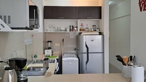 A modern kitchen with a built-in oven, microwave, and refrigerator. There is a sink with a dish rack, a kettle, and a coffee maker. The kitchen has a white countertop and dark wooden cabinets. - Alto Guemes I Spacious 1BR in Palermo (Buenos Aires)