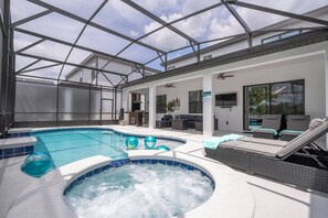 Une piscine avec un jacuzzi, des chaises longues et un patio couvert.