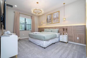Un dormitorio moderno con una cama grande, una mesita de noche, un aparador, un televisor y una ventana con cortinas.