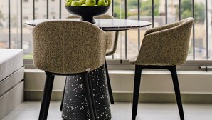 A balcony with a round table and two chairs, a bowl of green apples, and a view of buildings. - Loft do Colecionador I Stylish Loft in Jardins (São Paulo)