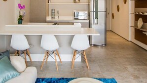 A modern kitchen with a central island, white bar stools, and a built-in refrigerator. - Vila Nova Amazing 1-bedroom in Vila Nova Concei o (São Paulo)