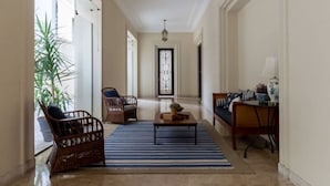 A hallway with a striped rug, wicker chairs, a wooden coffee table, and a decorative lantern. - Tiete Classic I Stunning 3 Bedroom in Jardins (São Paulo)