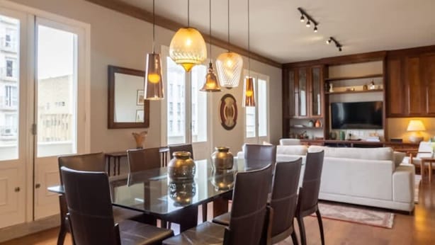 A spacious dining area with a glass table and dark chairs, a kitchen with wooden cabinets, and a living area with a sofa and TV. - Tiete Classic I Stunning 3 Bedroom in Jardins (São Paulo)