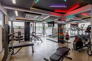 A gym with various exercise equipment, large windows, and a view of the outside. - Ator - Chic Studio in Vila Olimpia (São Paulo)