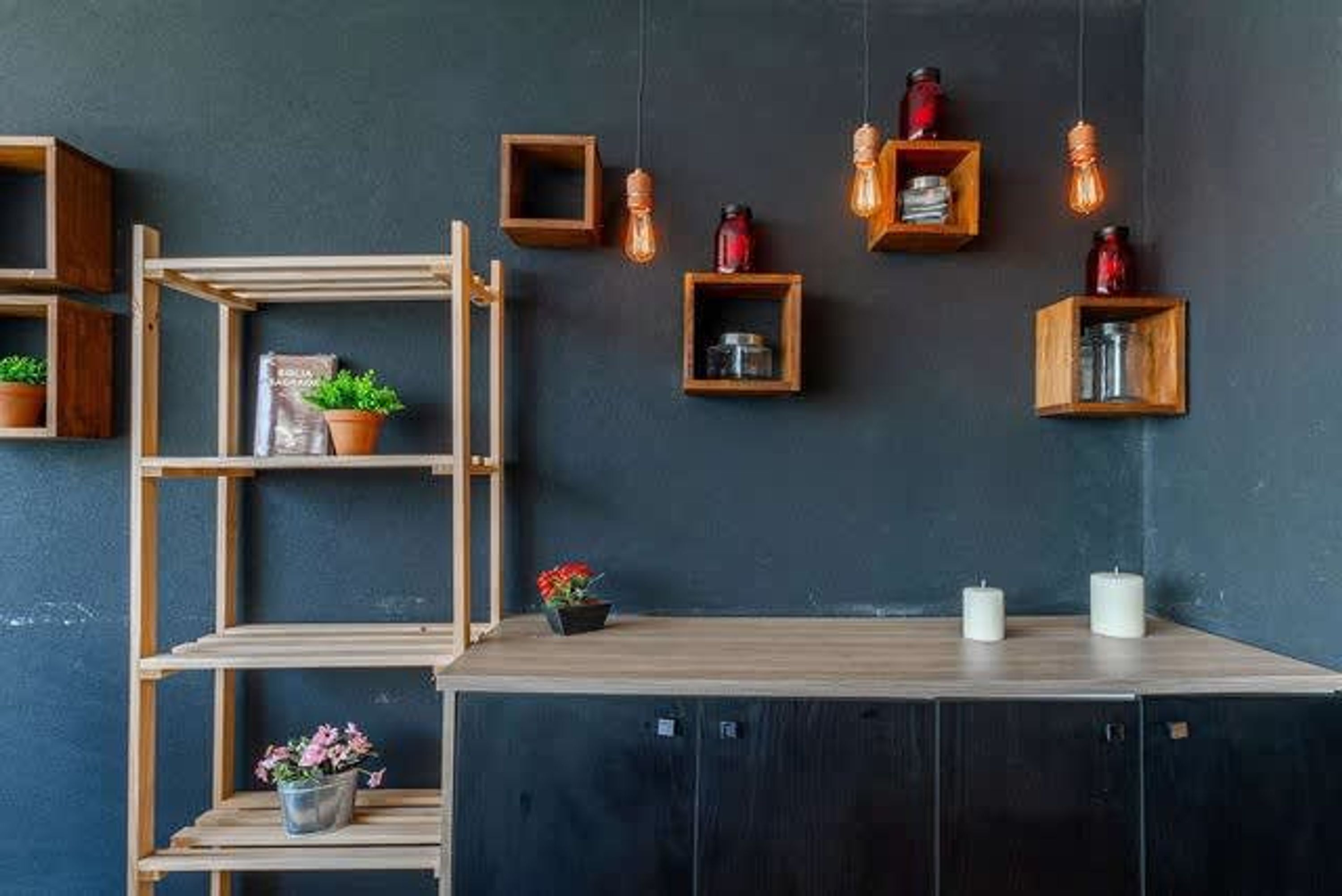 A room with a dark wall, wooden shelves, and a wooden cabinet.