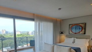 Une chambre d’hôtel moderne dotée d’un grand lit, d’un canapé, d’une petite table et d’un balcon offrant une vue sur la ville.