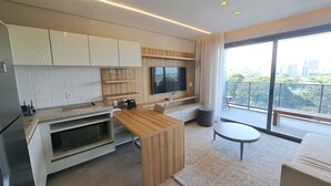 Une cuisine moderne dotée d’un îlot central en bois, d’appareils électroménagers intégrés et d’une grande fenêtre donnant sur un paysage urbain.