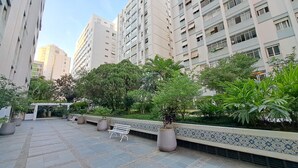 A courtyard with a tiled floor, benches, potted plants, and a tiled wall. - Jardins Vintage I Chic 1-br Office in Jardins (São Paulo)