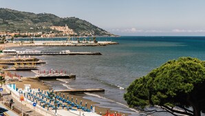 Un pueblo costero con playa, muelle y una colina con edificios.