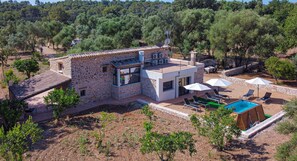 A stone house with a pool, outdoor seating, and a view of a forested hill. - Ses Rotes by Rentallorca (Campanet)
