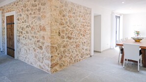 Et moderne interiør med en væg i natursten, en trädør og et spiseområde med bord og stole.